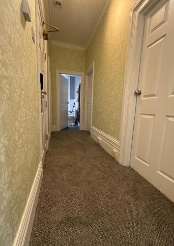 an empty hallway with green walls and a white door at Welbeck Hotel & Apartments IOM in Douglas