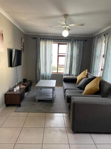 a living room with a couch and a table at Blossom on 13 in Gqeberha