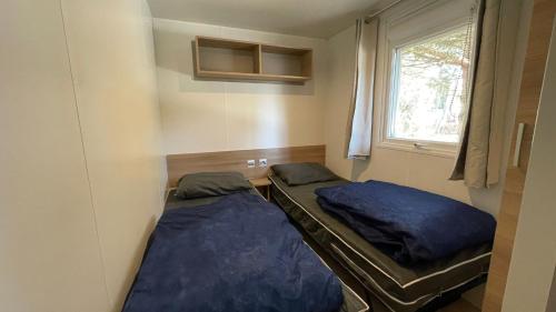 deux lits dans une petite pièce avec une fenêtre dans l'établissement Pleasant 3bed Mobilhome Siblu Bonne Anse La Palmyre, aux Mathes