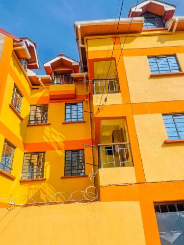 a tall yellow building with lots of windows at Zedek Suites in Nairobi