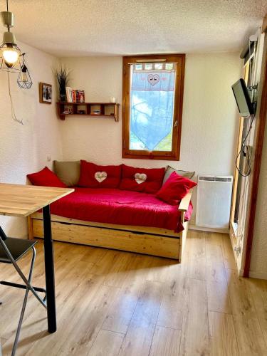 - un canapé rouge dans une chambre avec fenêtre dans l'établissement Bel appartement cosy PIED DES PISTES avec local ski LA PLAGNE, à Aime La Plagne
