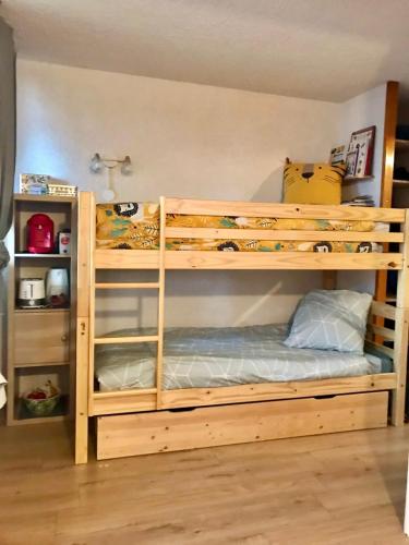 Ce lit superposé en bois se trouve dans un dortoir. dans l'établissement Bel appartement cosy PIED DES PISTES avec local ski LA PLAGNE, à Aime La Plagne