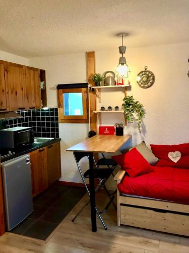 une cuisine avec un canapé rouge et une table dans l'établissement Bel appartement cosy PIED DES PISTES avec local ski LA PLAGNE, à Aime La Plagne
