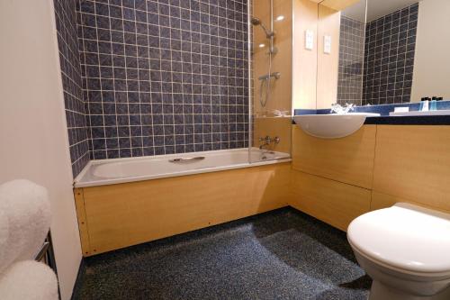 a bathroom with a tub and a toilet and a sink at Gomersal Park Hotel & Bazaar Spa in Cleckheaton