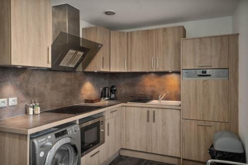 - une cuisine avec des placards en bois et un lave-linge dans l'établissement Appartement tout confort entre Versailles & Paris - Calme et 2 chambres équipées, à Le Port-Marly