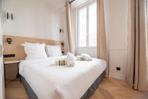 un grand lit blanc dans une chambre avec une fenêtre dans l'établissement Bastille - Crémieux Residence, à Paris