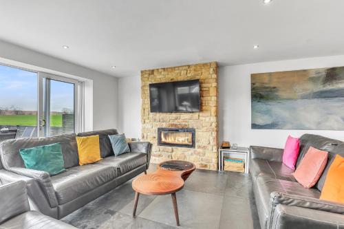 a living room with two leather couches and a fireplace at The Duchess - North East Escapes in Bamburgh