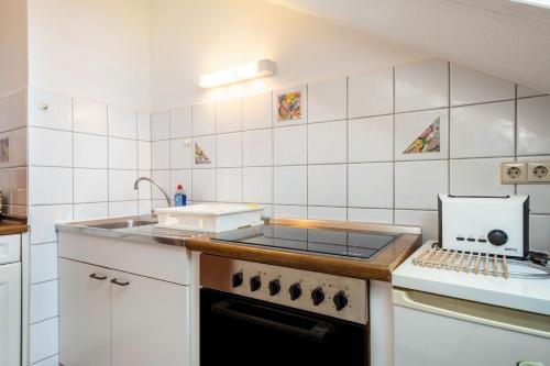 a white kitchen with a stove and a sink at Hotel Garni Vitamari in Wasserburg am Bodensee