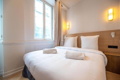une chambre avec deux lits avec des draps blancs et une fenêtre dans l'établissement Austerlitz-Bastille Residence, à Paris