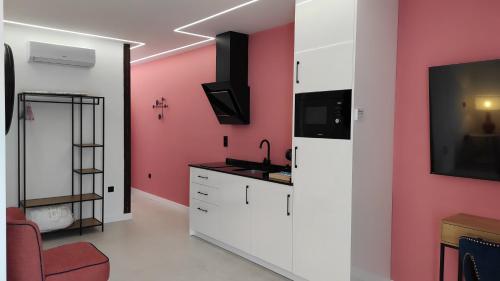 a kitchen with pink walls and a sink and a tv at Apartamentos Ritual Casablanca in Torremolinos