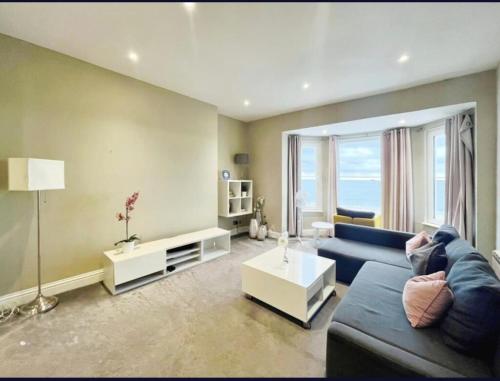 a living room with a blue couch and a table at Stones Throw From The Beach - Stunning Sea View in Portsmouth