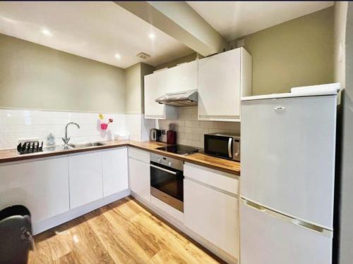 a kitchen with white cabinets and a refrigerator at Stones Throw From The Beach - Stunning Sea View in Portsmouth