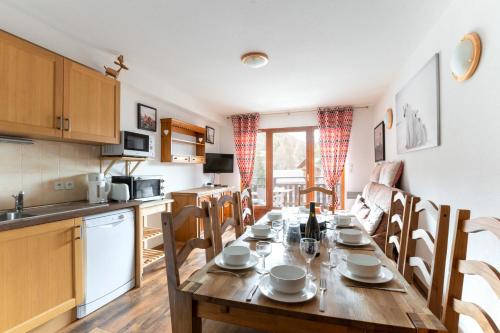 une cuisine et une salle à manger avec une table et des chaises en bois dans l'établissement Au coeur de la station pour 8 personnes, à Saint-Étienne-en-Dévoluy