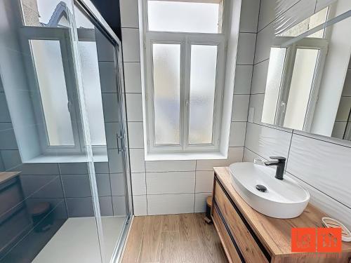 une salle de bain avec un lavabo et un miroir dans l'établissement Le Petit Edmond, à Wimereux