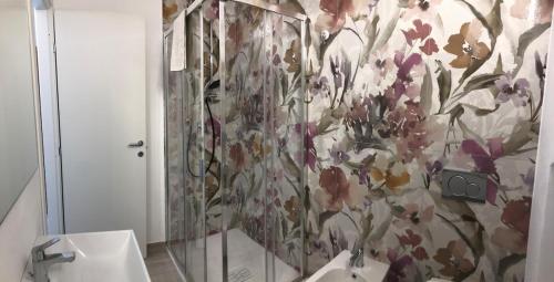 a bathroom with a shower with a floral wallpaper at Dantis Domus at the beach in Levanto