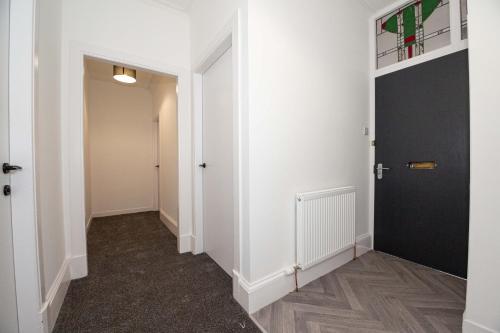a hallway with white walls and a black door at Carnoustie Residence - SJA Stays - 3 Bed Apartment in Carnoustie