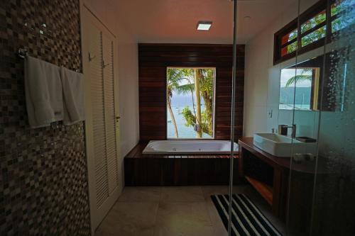 a bathroom with a tub and a sink and a window at Casa da Ilha & SPA in Abraão