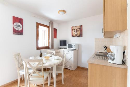 - une cuisine avec une table et une table et des chaises blanches dans l'établissement La Joue du Loup, appartement pour 4, balcon, à Saint-Étienne-en-Dévoluy
