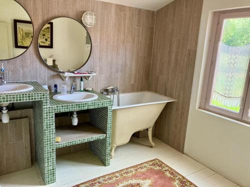 une salle de bain avec deux lavabos, une baignoire et un miroir dans l'établissement Grande maison entre mer et fôret, à La Celle-sous-Gouzon