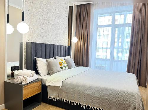 a bedroom with a bed and a large window at Красивая евродвушка на Левом берегу Астаны, район ЭКСПО in Astana