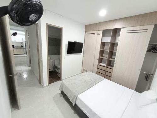 a white bedroom with a bed and a bathroom at Apartamentos en Club Residencial in Ibagué