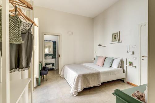 a white bedroom with a bed and a mirror at B&B Fiore in Gallipoli