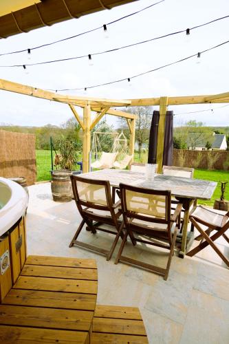 un patio avec une table et des chaises sous un pavillon dans l'établissement Maison de vacances avec SPA, à Martinvast