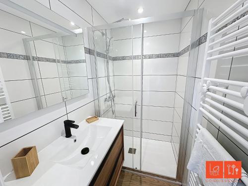 une salle de bain blanche avec un lavabo et une douche dans l'établissement La Grande Augustine, à Wimereux
