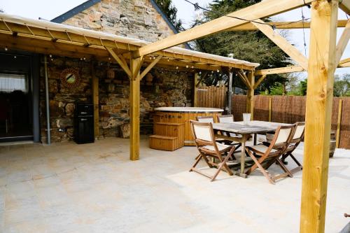 a wooden pavilion with a table and chairs on a patio at Maison de vacances avec SPA in Martinvast