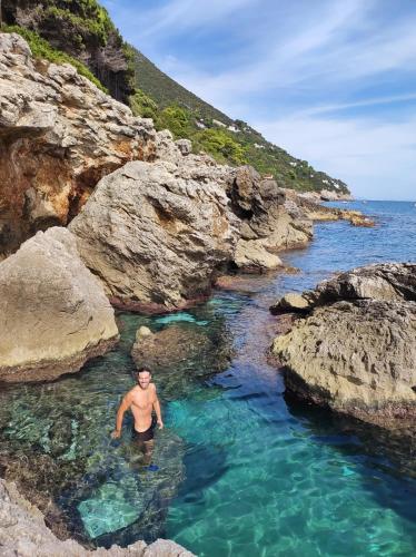 a man in a pool of water on a rocky beach at Eco House San Michele in San Michele