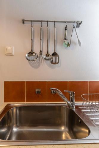 a kitchen sink with utensils hanging on a wall at Palazzo Corfu Suite in Corfu