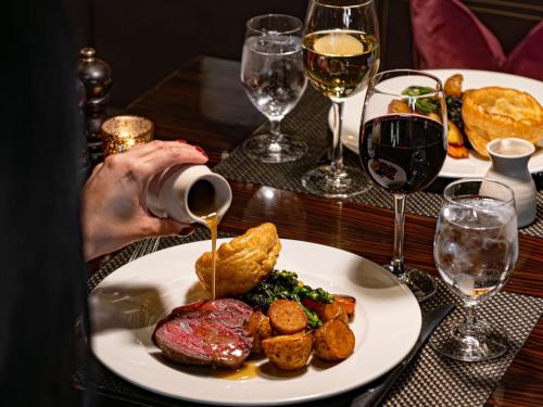 a person is pouring wine into a plate of food at Dakota Eurocentral in Motherwell