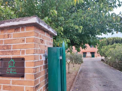 a brick wall with a green door next to a road at Eco House San Michele in San Michele