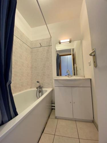 une salle de bain avec une baignoire, un lavabo et un miroir dans l'établissement Les Monts du soleil, La joue du loup, à La Joue du Loup