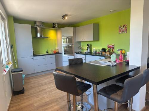 une cuisine avec des murs verts et une table et des chaises dans l'établissement Apparemment Vias plage-village, à Vias