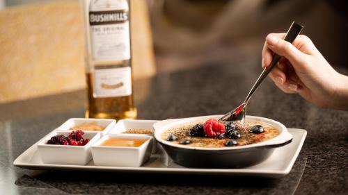 a person eating a plate of pancakes with berries and syrup at Europa Hotel in Belfast