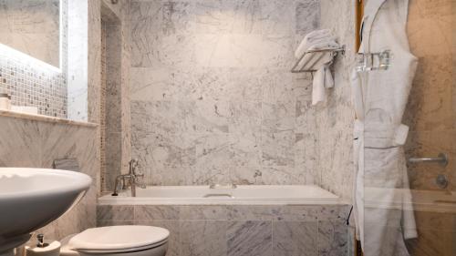 a bathroom with a tub and a toilet and a sink at Europa Hotel in Belfast