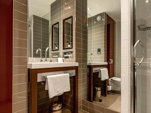 a bathroom with a sink and two mirrors and a toilet at Dakota Eurocentral in Motherwell