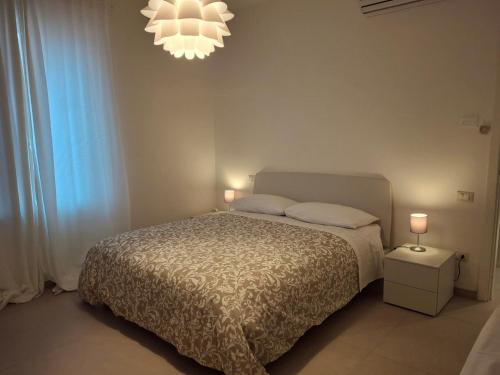 a bedroom with a bed and a chandelier at Maresol apartment in Carrara