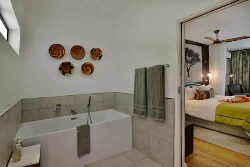 a bathroom with a tub and a bedroom with a bed at Cresta Mowana Safari Resort & Spa in Kasane