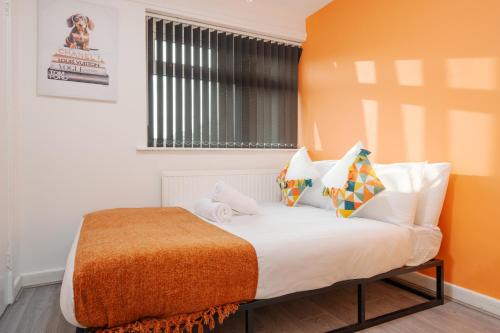 a bedroom with a bed with an orange headboard at The Jade - Pool Table - Man Utd - City Centre - 4bd in Manchester