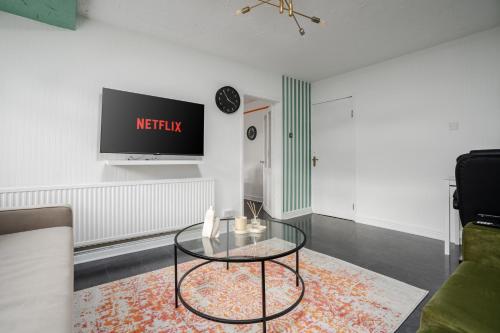 a living room with a glass table and a tv at The Jade - Pool Table - Man Utd - City Centre - 4bd in Manchester