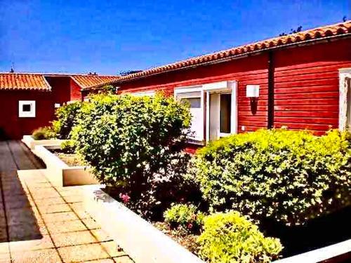 une maison rouge avec des buissons devant elle dans l'établissement Vue sur le Vieux Port, à La Rochelle