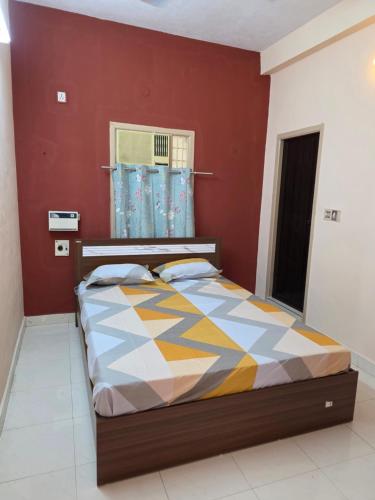 a bed in a room with a red wall at RS Apartments in Tiruvannāmalai