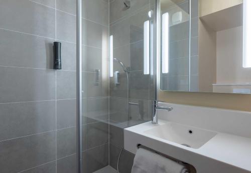 une salle de bain avec une douche, un lavabo et un miroir dans l'établissement B&B HOTEL Saint-Pierre-en-Faucigny Bonneville, à Saint Pierre en Faucigny
