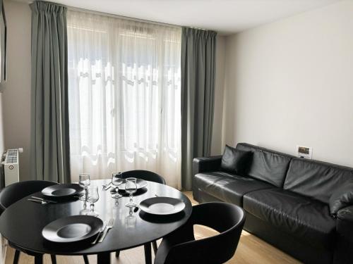 - un salon avec une table et un canapé en cuir noir dans l'établissement Les Maisons d'Eugène Appart'Hôtel - Centre Historique, à Honfleur