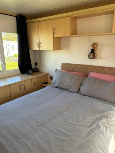 a bedroom with a large bed with pink and gray pillows at 148 Port Haverigg in Millom