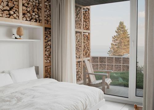 a bedroom with a bed and a balcony with a window at La Petite Bûche #1 in La Malbaie