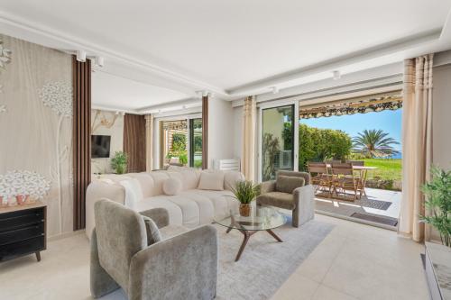 un salon avec un canapé blanc et des chaises dans l'établissement Luxueux Appartement avec Jardin Suspendu Vue Mer 10 min du Palais Cannes, à Cannes