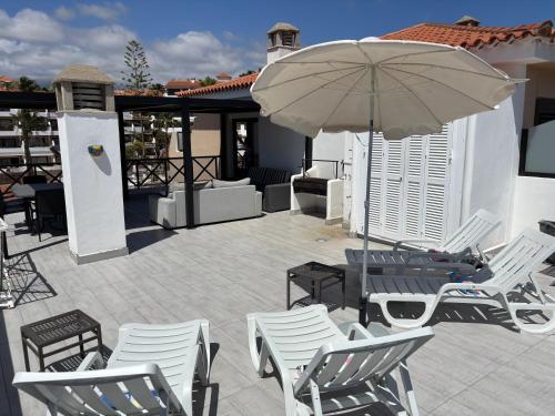 Un patio con una mesa y sillas y una sombrilla. en Golf del Sur Parque Albatros 417, en San Miguel de Abona